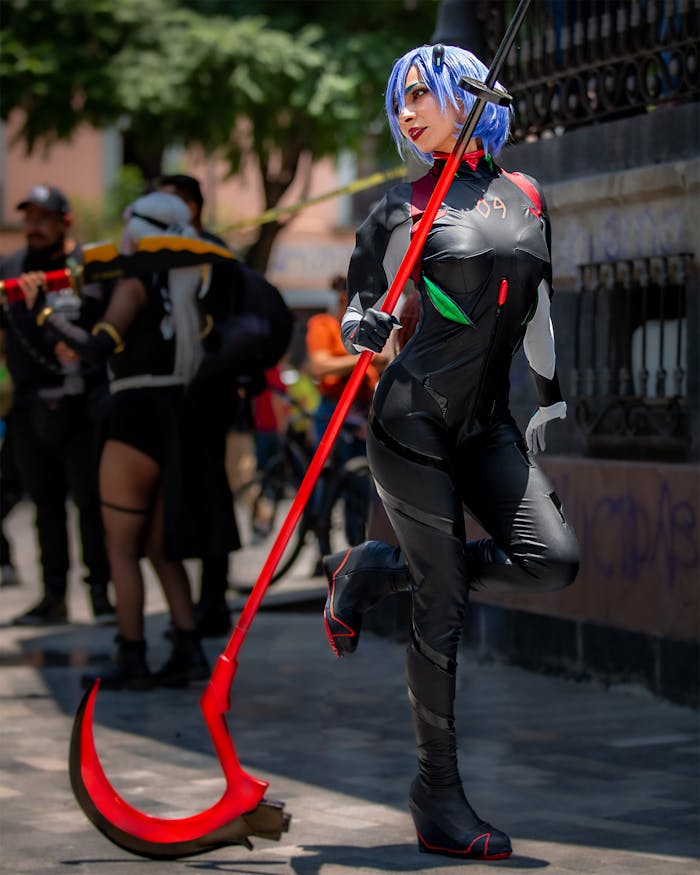 Cosplayer in black suit with red weapon posing as anime character outdoors in Mexico City.